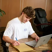 Sepp schrijft aantekeningen naast zijn laptop
